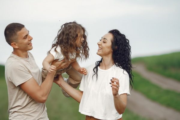 A joyful family moment outdoors with parents playing with their daughter.