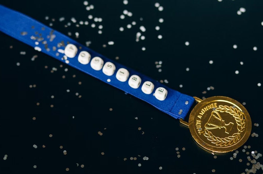 Close-up of a gold medal on a blue ribbon with 'possible' beading, symbolizing achievement.